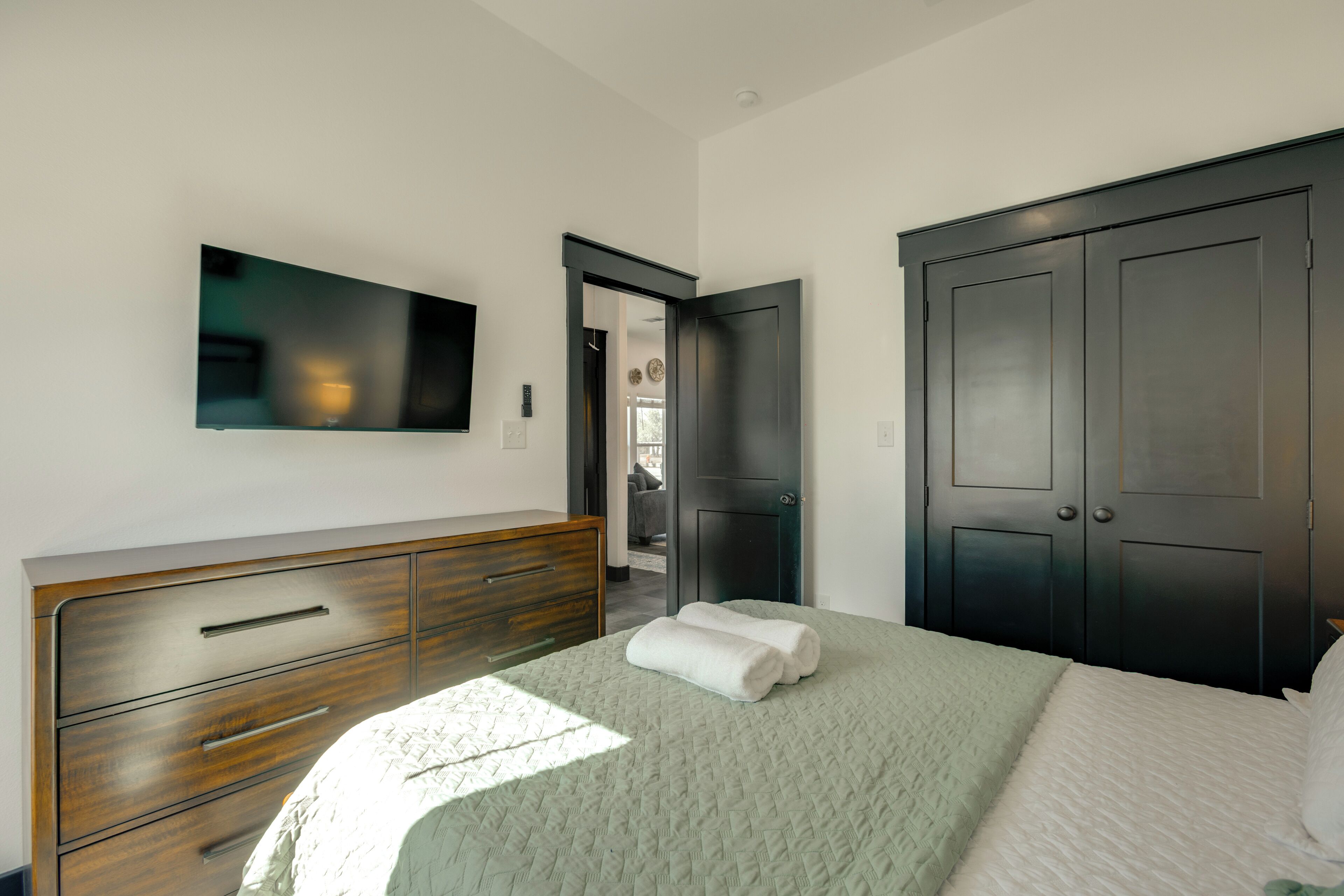 A bedroom with a bed, a dresser, a wardrobe, and a TV mounted on the wall.