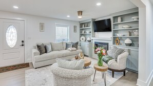 A modern living room with a sofa, armchairs, a coffee table, and a fireplace. - East Texas Group Getaway! Modern Longview Home (Longview)