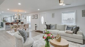 A spacious living area with a sofa, a coffee table, and a dining table with chairs. - East Texas Group Getaway! Modern Longview Home (Longview)