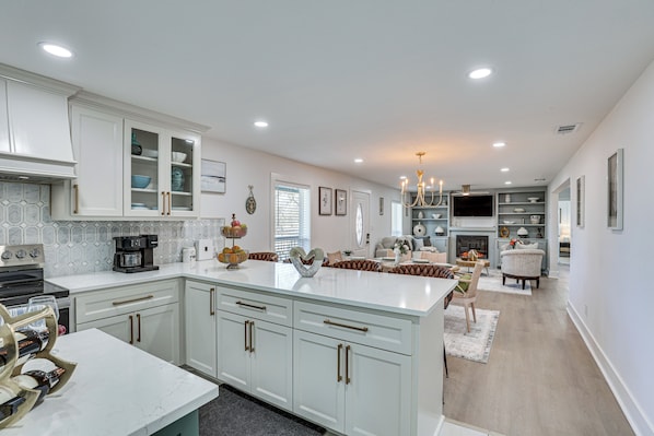 A spacious kitchen with white cabinetry, a marble countertop, and a central island. - East Texas Group Getaway! Modern Longview Home (Longview)
