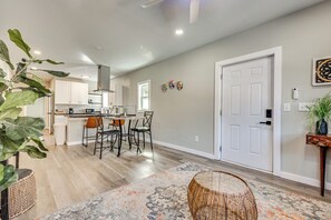A modern kitchen with white cabinets, a dining area with chairs, and a large window.