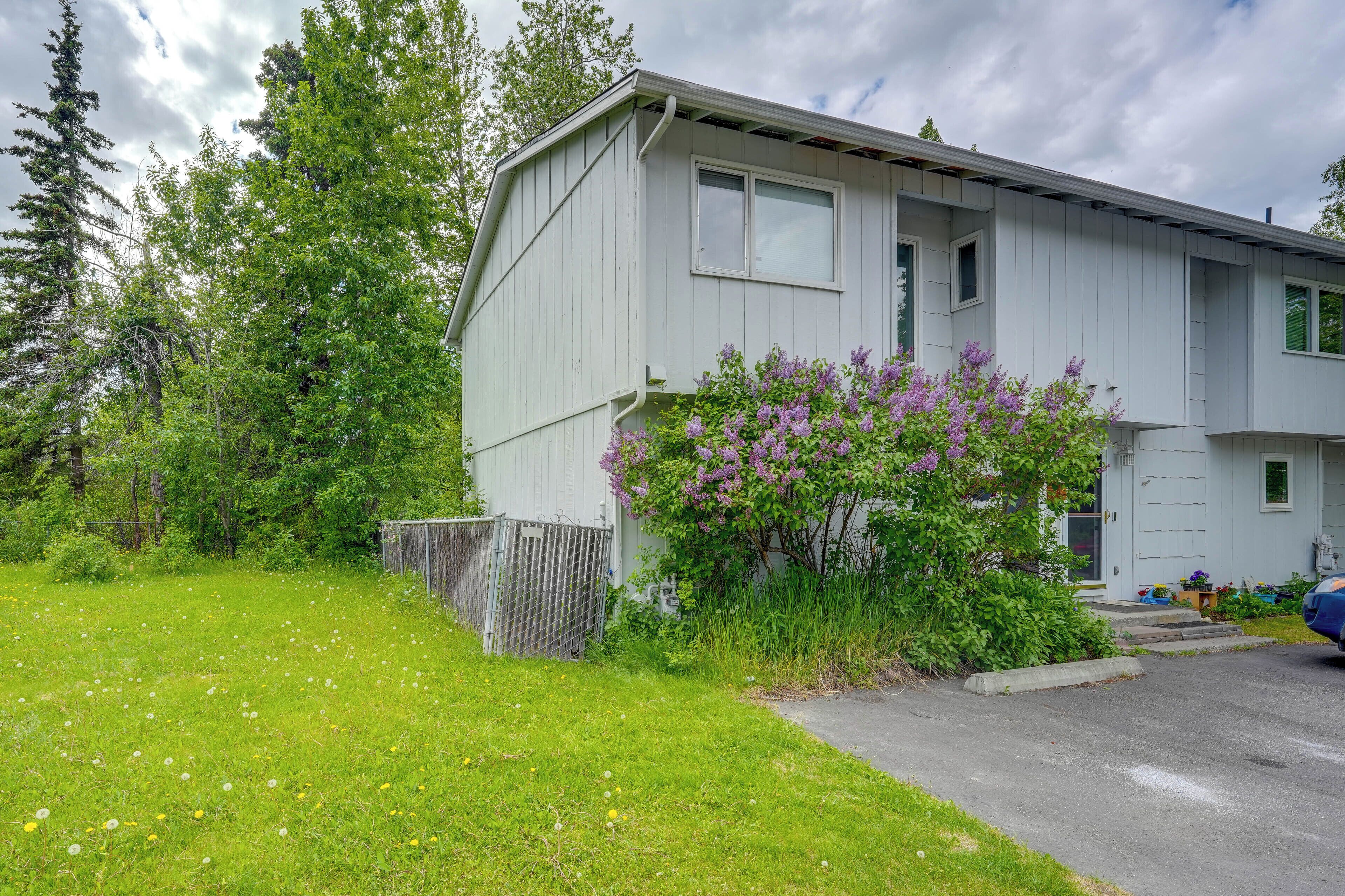 A two-story building with a front yard, a small garden, and a parked car.