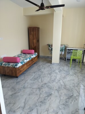 Un dormitorio con cama, armario, escritorio y silla.