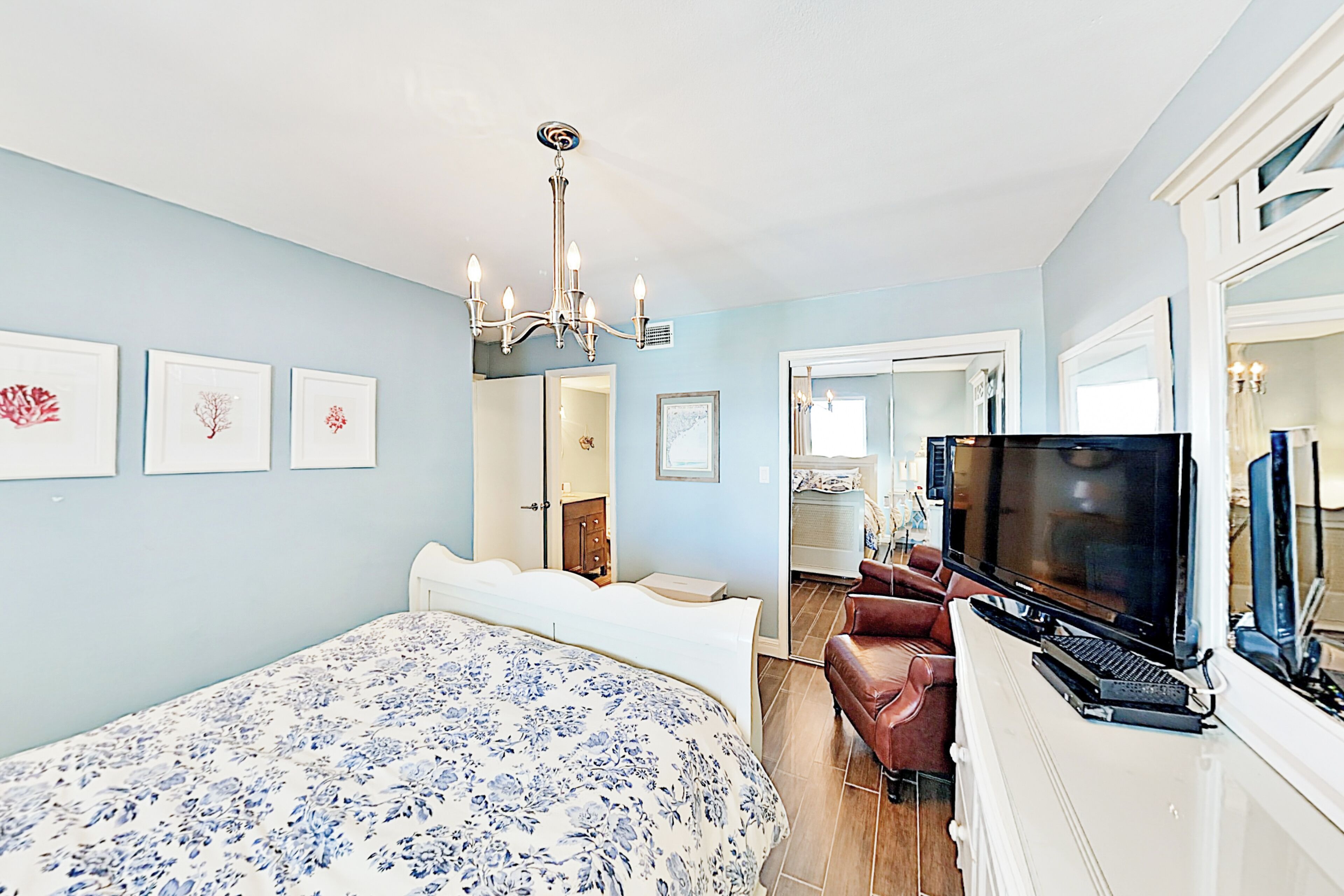 A bedroom with a large bed, a TV, and a desk with a laptop.