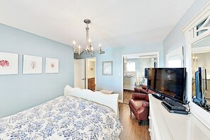 Un dormitorio con una cama grande, un televisor y un escritorio con una computadora portátil.