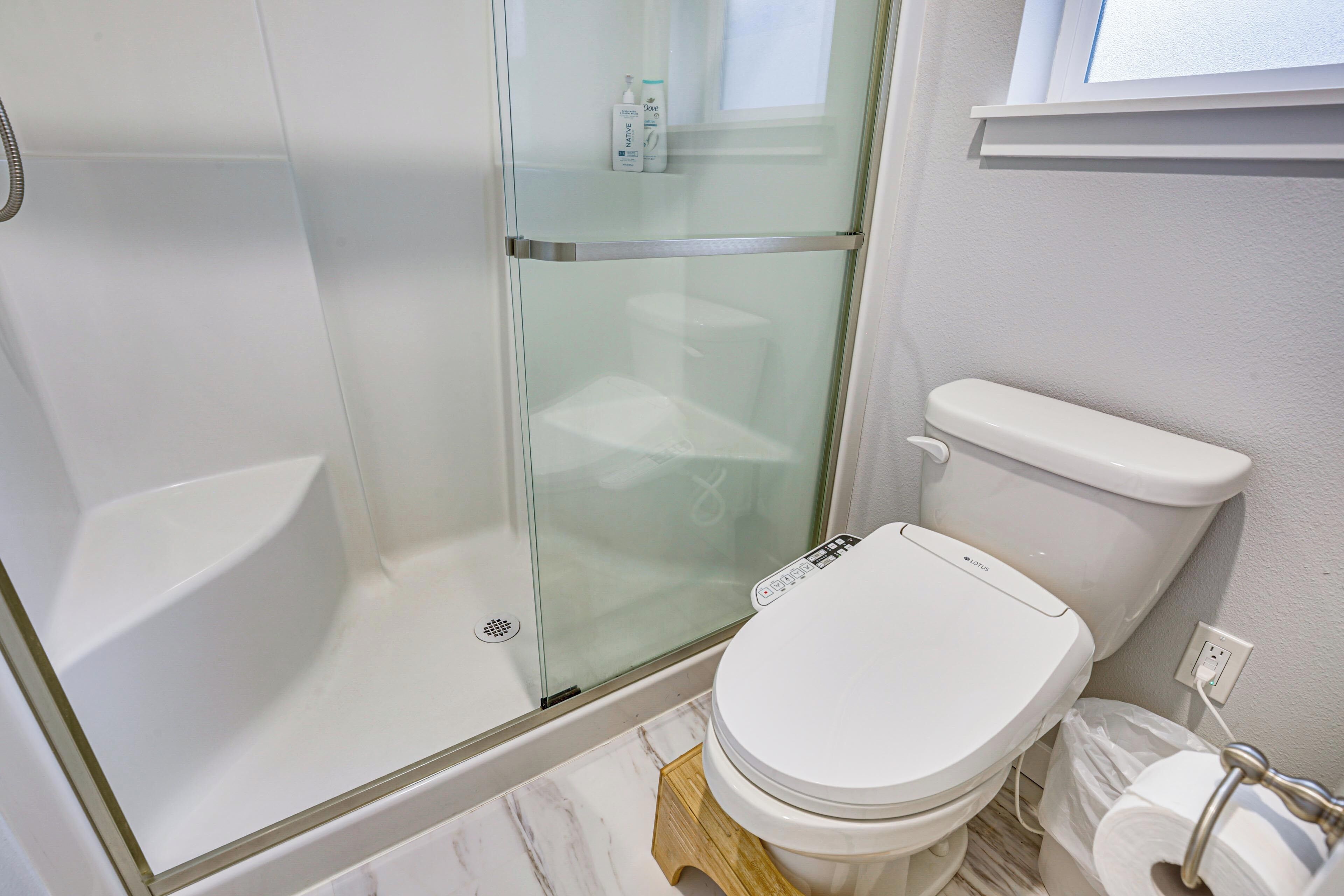 Une salle de bain dotée d’une douche à parois de verre, de toilettes et d’un sol en marbre.