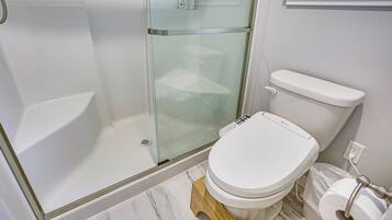 Une salle de bain dotée d’une douche à parois de verre, de toilettes et d’un sol en marbre.