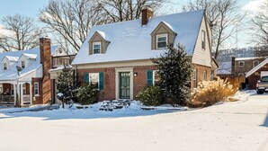A two-story brick house with a snow-covered roof and a green door.