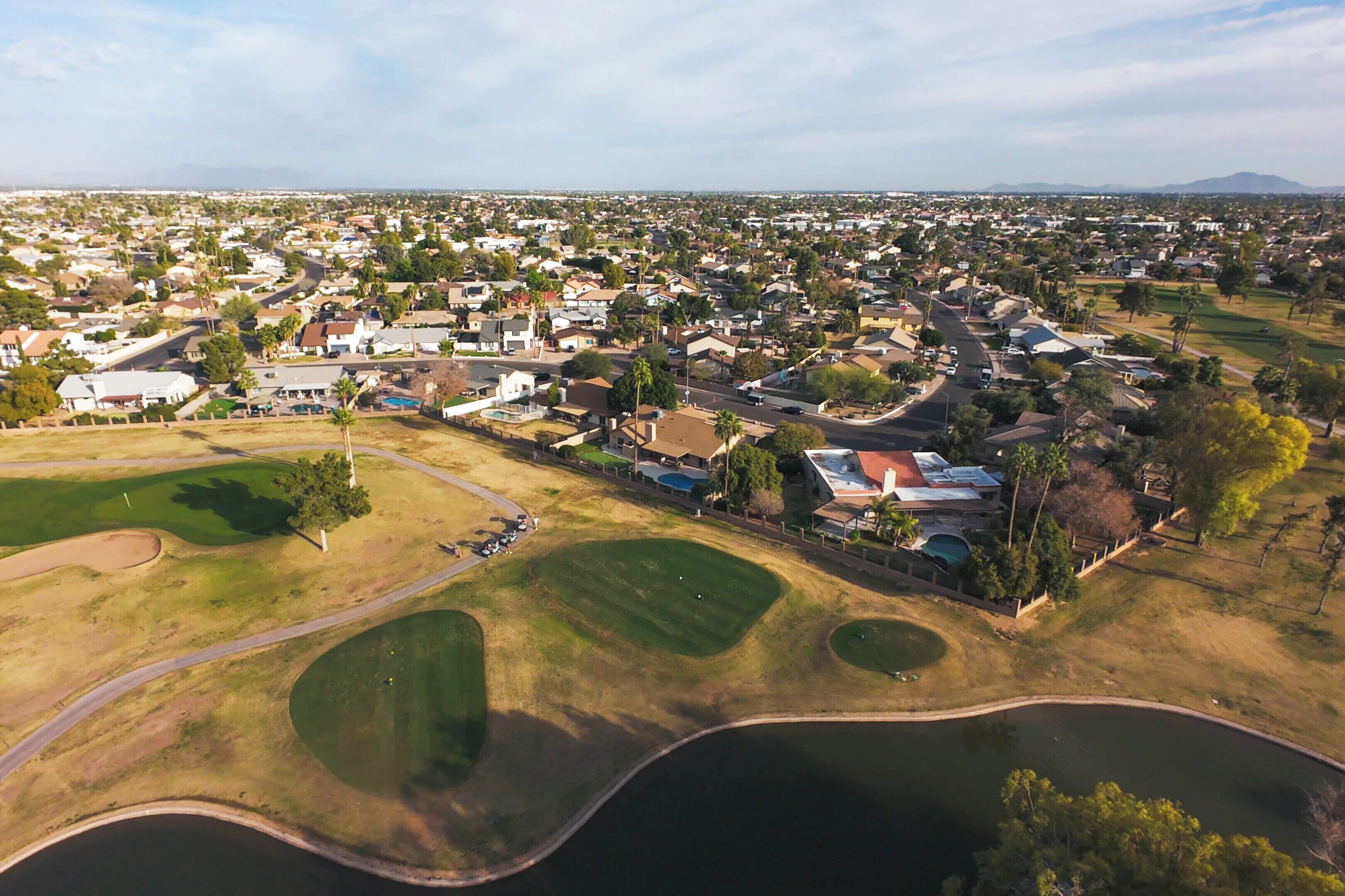 An aerial view of a residential area with houses, roads, and a golf course.