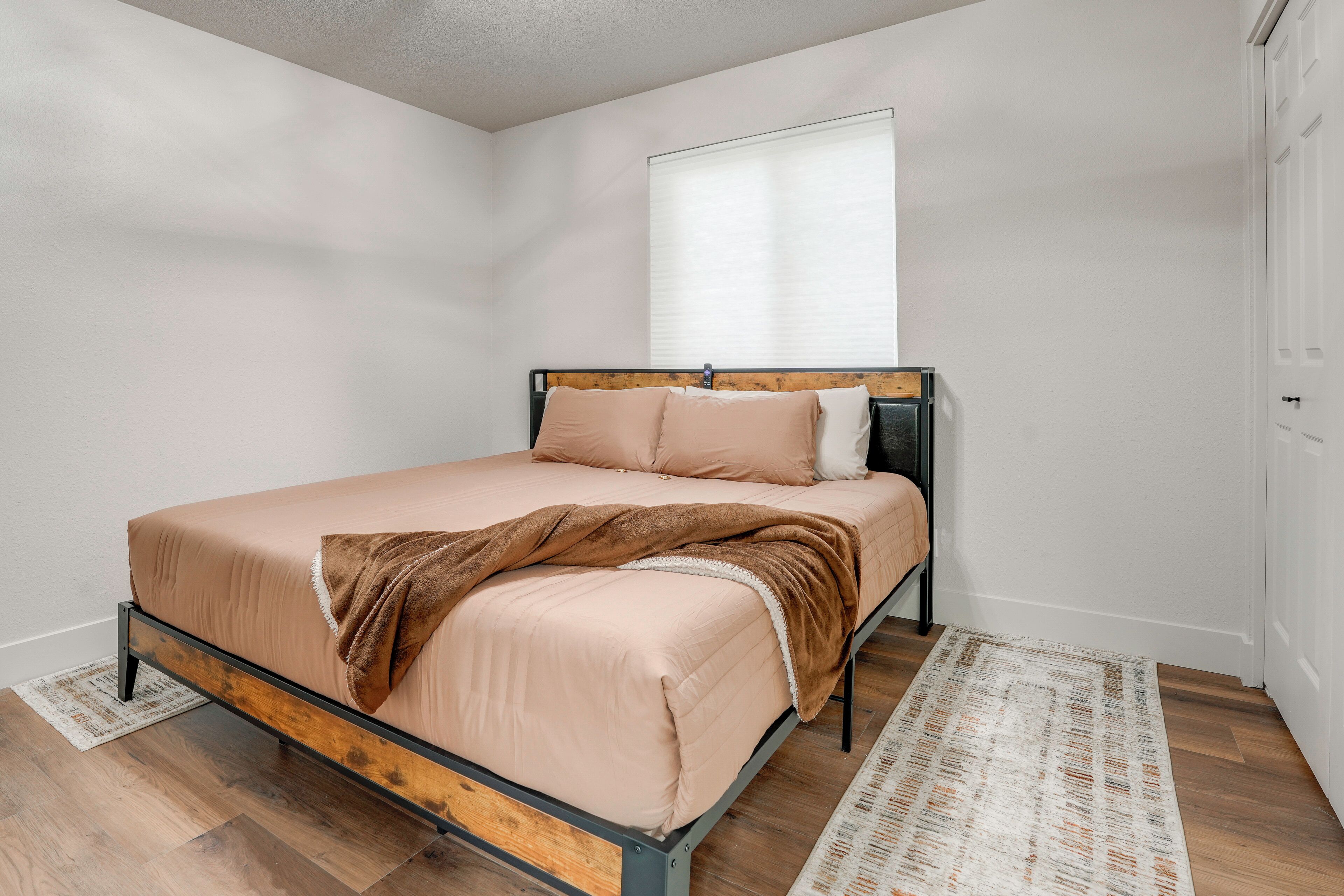 A bedroom with a bed, a window, and a door.