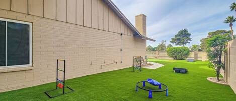 A well-maintained outdoor area with artificial grass, a swing set, and a climbing frame.