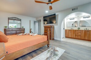 Ein Schlafzimmer mit einem hölzernen Bett, einem Deckenventilator, einem großen Spiegel und einem an der Wand montierten Fernseher.