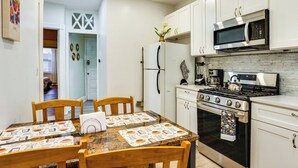 Une cuisine de taille réduite avec des meubles blancs, une cuisinière en acier inoxydable et un four à micro-ondes.