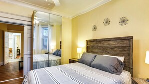 Une chambre à coucher avec un grand lit, une tête de lit en bois, une table de chevet et un miroir.