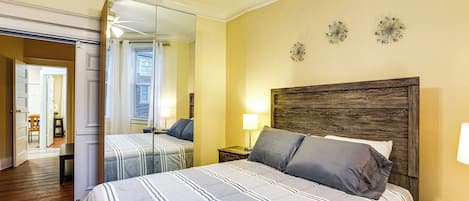 Un dormitorio con una cama grande, cabecera de madera, una mesita de noche y un espejo.