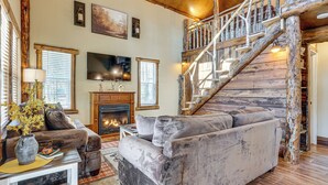Un salon chaleureux avec une cheminée, un grand canapé et un escalier en bois.