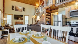 Un intérieur rustique comprenant un coin repas, une cuisine et un escalier.