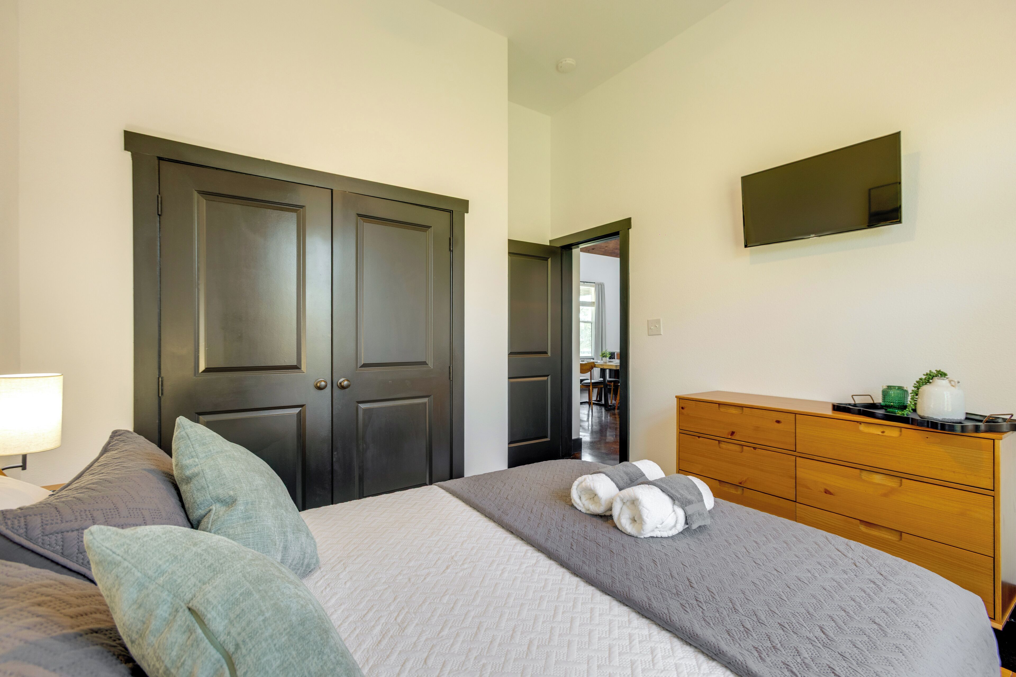 Un dormitorio con cama, cómoda, espejo y puerta.