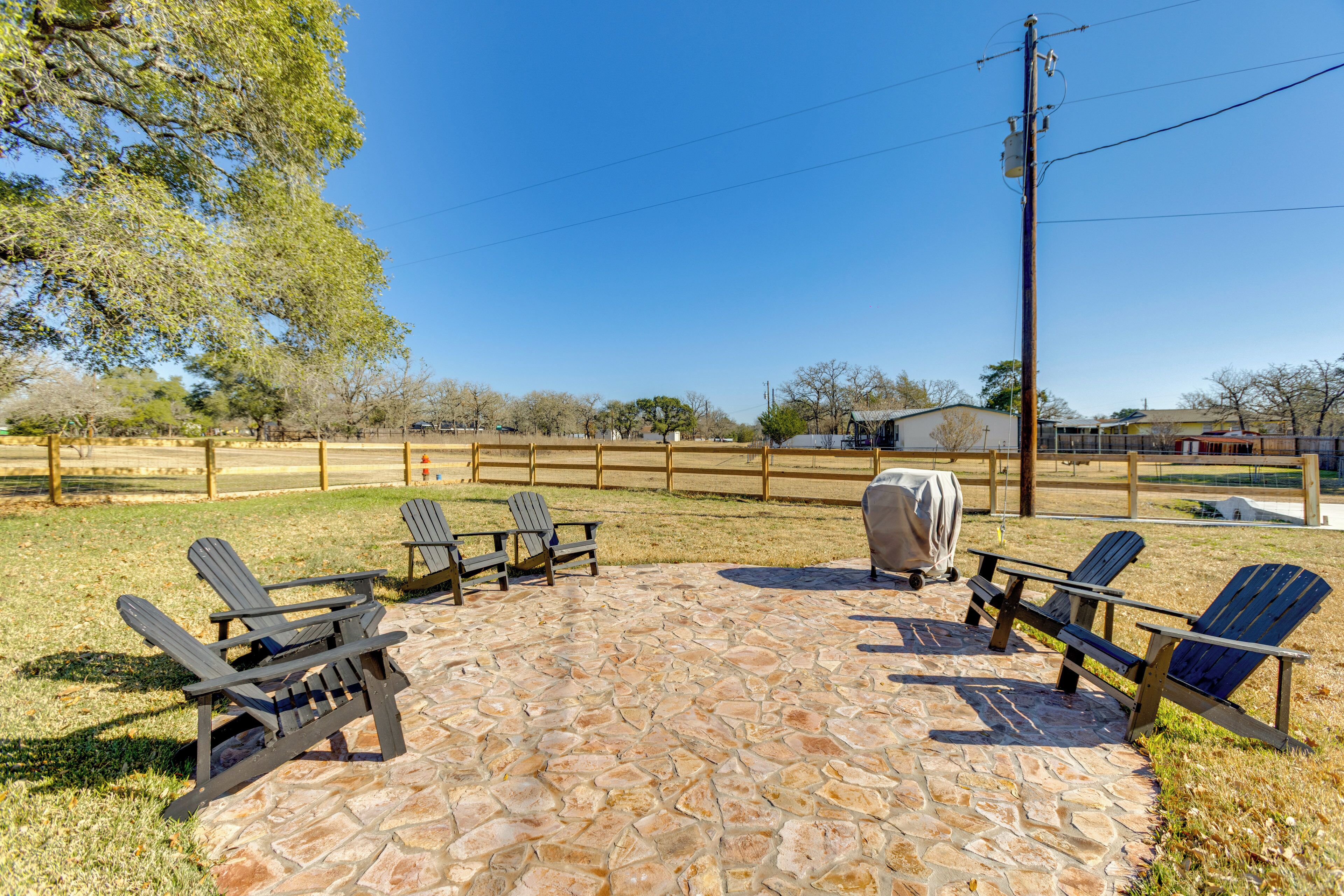 Un patio con sillas Adirondack, una parrilla y piso de baldosas de piedra.