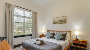 A neatly arranged bedroom with a bed, bedside tables, a window with curtains, and a painting on the wall. - Modern 2BR Near Lake Somerville & Round Top (Somerville)