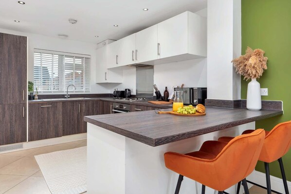 A modern kitchen with a central island, dark wood cabinets, and a green accent wall.