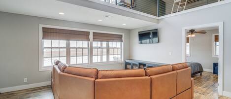 Un amplio salón con sofá modular, ventanas grandes y balcón.