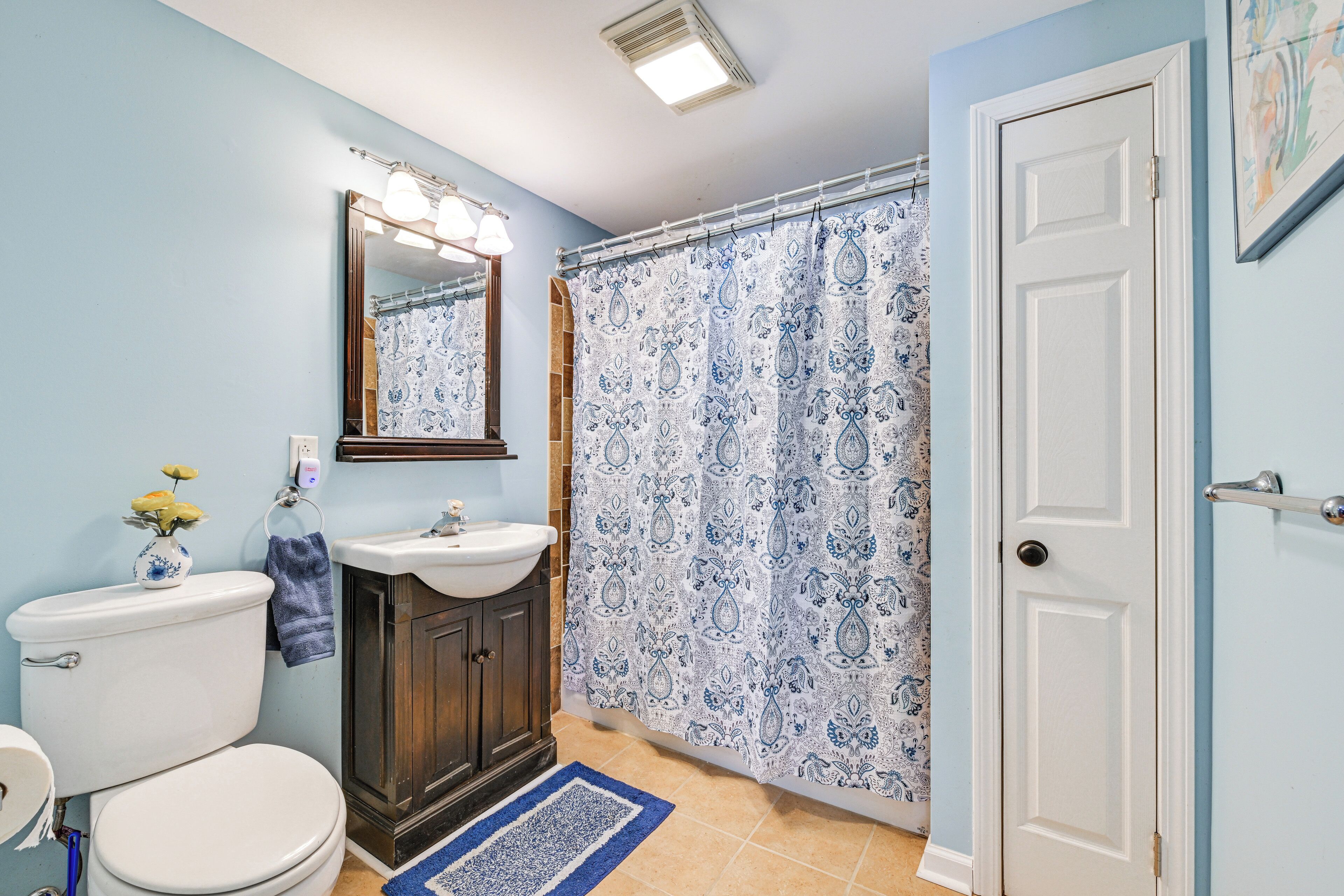 A bathroom with a toilet, sink, mirror, and shower curtain.