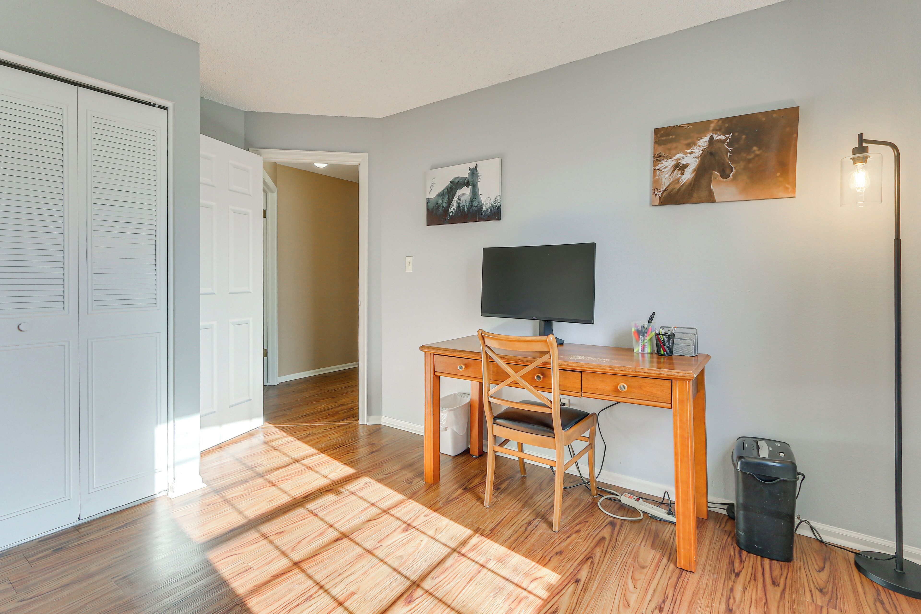 A room with a wooden desk, a chair, a computer, and a trash can.