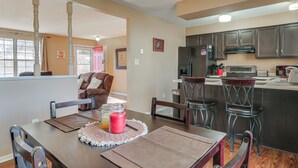 A dining area with a wooden table, chairs, and a kitchen in the background. - 4 Mi to Dtwn Loveland: Home w/ Hot Tub & Yard (Loveland)