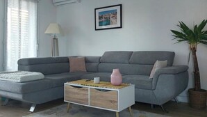 A modern living room with a grey sofa, a white coffee table, a lamp, and a framed picture on the wall.
