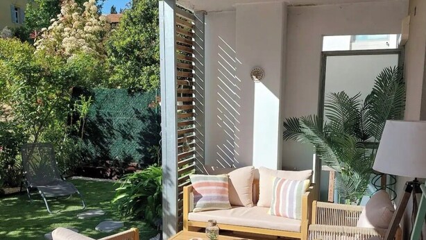 An outdoor patio with wicker furniture, a cushioned sofa, and a coffee table.