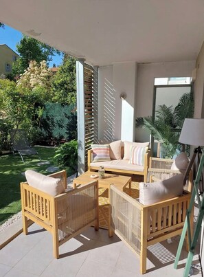 Eine Terrassengruppe im Freien mit Korbmöbeln, einer gepolsterten Couch und einem Couchtisch.