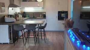 A modern kitchen with a central island, bar stools, and a dining area.