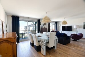 Un salon moderne comprenant un coin repas, un canapé, un téléviseur et une vue sur l’extérieur.