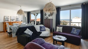 Ein geräumiges Wohnzimmer mit Essbereich, großen Fenstern und Aussicht sowie einem Balkon.