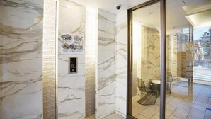 A modern hotel lobby with marble walls, a glass door leading to a bathroom, and a security camera. - Chuan House Kuromon (Osaka)