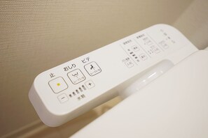 Un panneau de commande avec du texte et des symboles en japonais, probablement pour des toilettes.