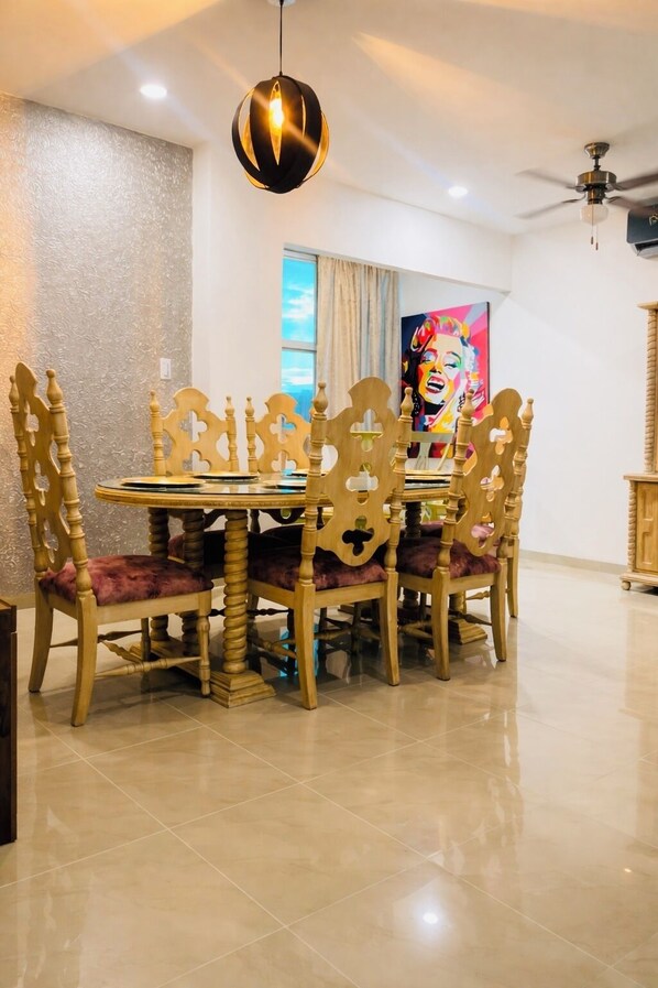 A dining area with a round table and ornate chairs, a ceiling fan, and a painting on the wall. - Super location apartment in the north of the city (Montería)