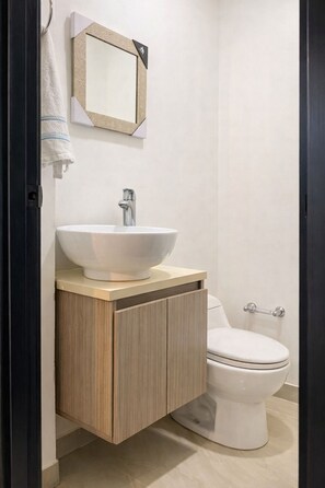 A modern bathroom with a white sink, wooden vanity, and a toilet. - Super location apartment in the north of the city (Montería)