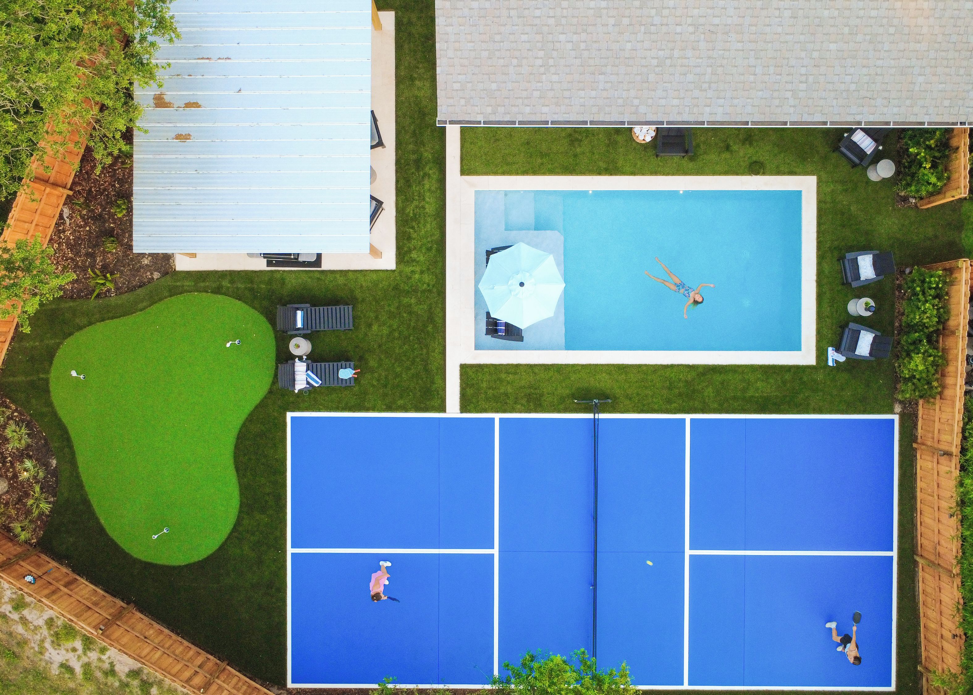 A rooftop with a swimming pool, tennis court, and a small garden area.
