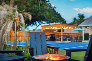 A poolside area with a fire pit, outdoor seating, and a covered patio. - Heated Pool | Pickleball | Golf Cart | Putting (Jacksonville Beach)