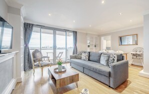Un salon moderne avec un canapé gris, une table basse en bois et une grande fenêtre avec des rideaux.