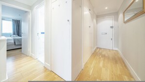 A room with a wooden floor, white walls, and a bed with a window view. - Stunning Flat in Chelsea Kings Road With Balcony (London)
