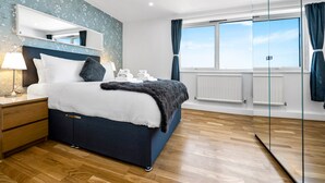 A bedroom with a large bed, a nightstand, a mirror, and a window with curtains. - Stunning Flat in Chelsea Kings Road With Balcony (London)