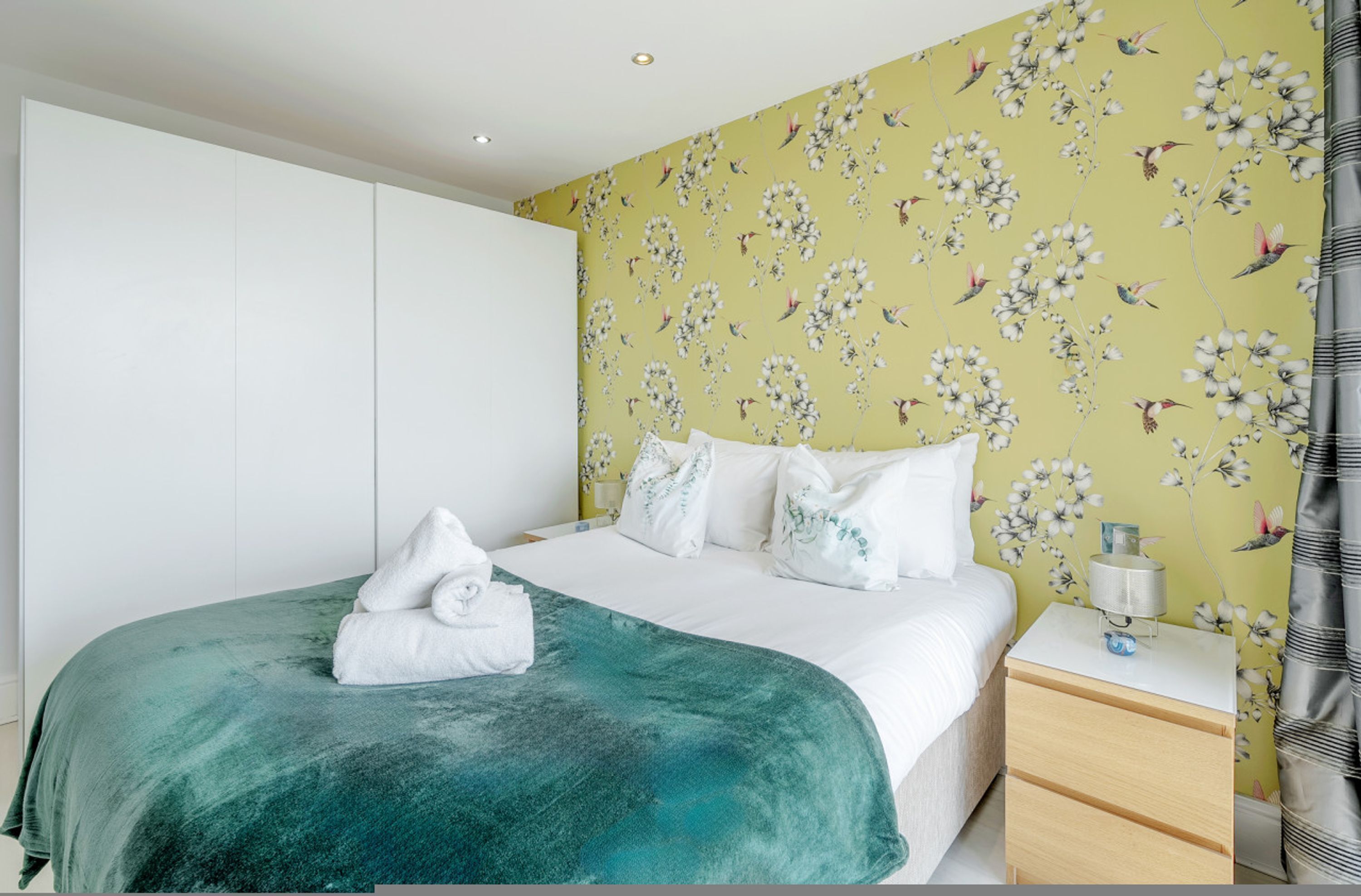 A bedroom with a bed, a nightstand, a drawer, and a wardrobe.