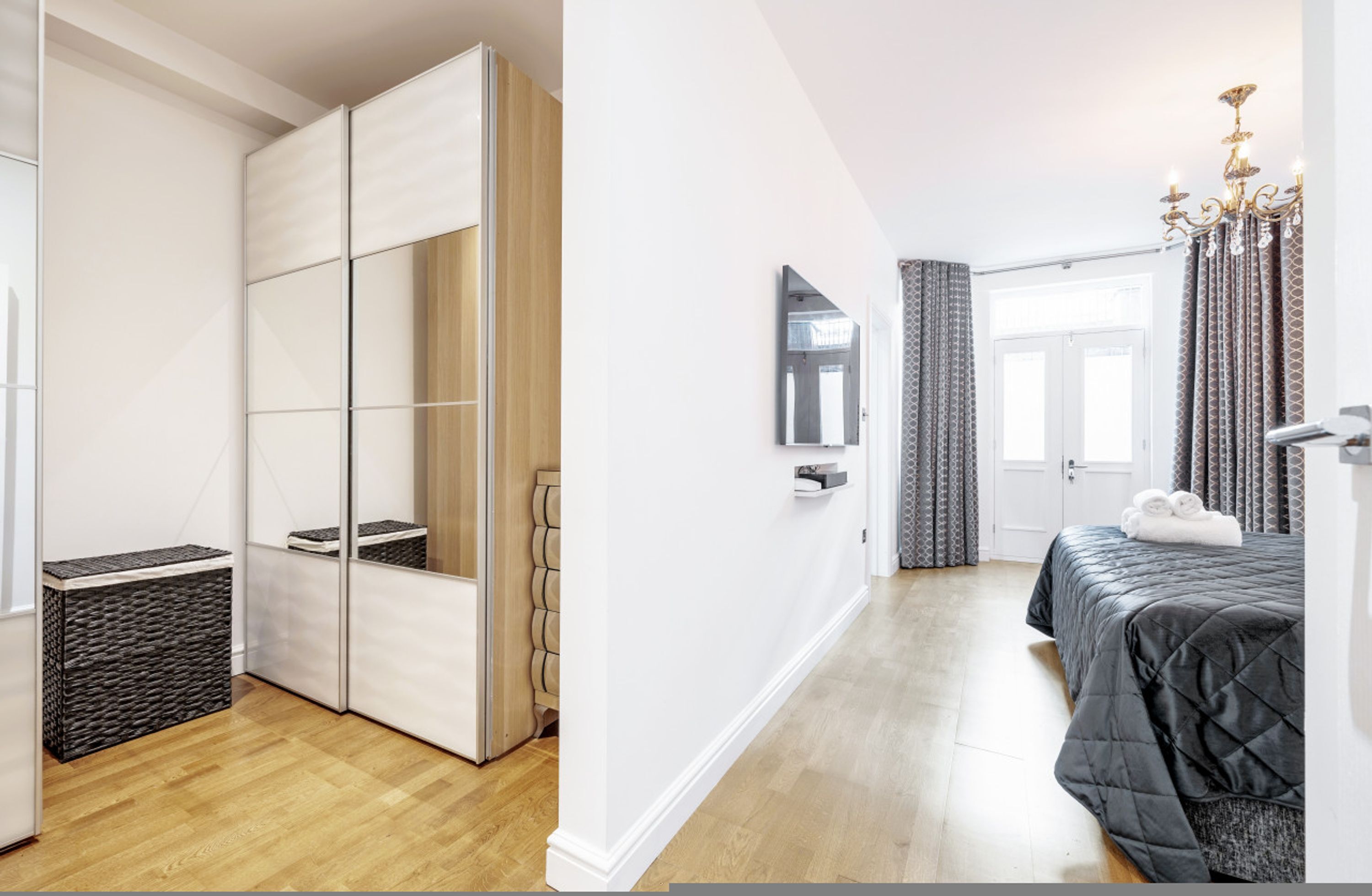 Quarto moderno com uma cama grande, um guarda-roupa, um espelho e um candelabro.