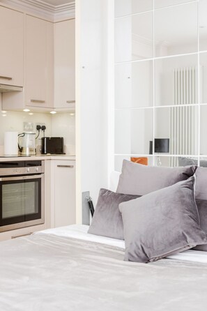 Een moderne slaapkamer met een groot bed, een nachtkastje en uitzicht op de keuken.