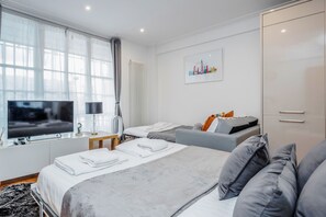 Een moderne hotelkamer met een groot bed, een kleinere bank, een televisie en een radiator.
