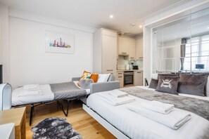 Een moderne hotelkamer met twee bedden, een bank, een eethoek en een keuken.