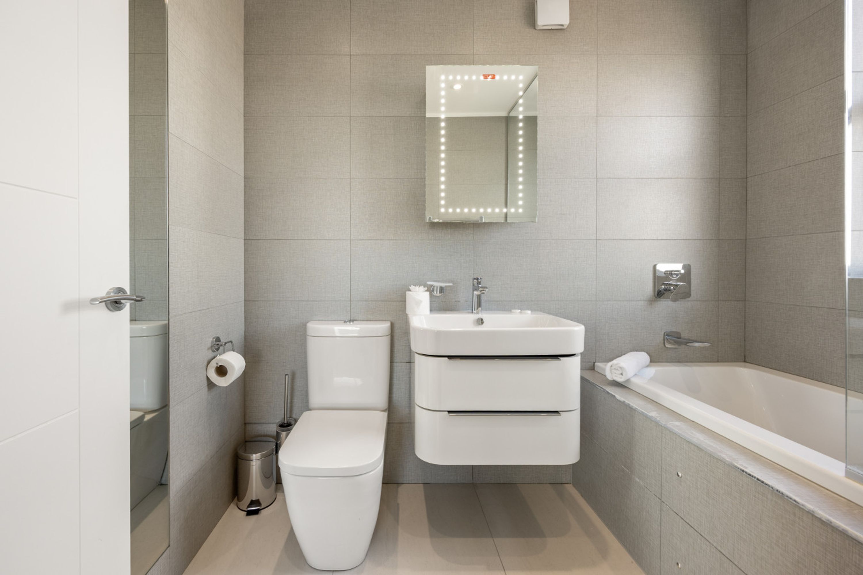 A modern bathroom with a toilet, sink, and bathtub.